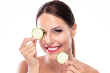 Şaşırtıcı bir esmer elinde salatalık dilimleri ve neşeyle gülümsüyor.