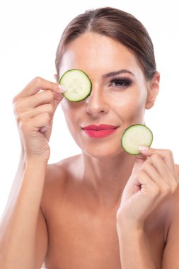 Güzel bir kadın salatalık dilimleriyle oynuyor ve gülümsüyor, cilt pürüzsüzlüğünü geliştiriyor. 