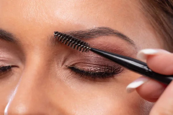 Making of stylish eyebrows on the face of a beautiful woman using eyebrow brush