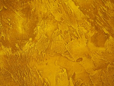 Duvarın yüzeyi pürüzlü, arka planda altın desenli boya var.