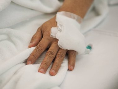 Hastalar yatakhanedeki koğuşta uyur. Hastanedeki kadının eline serum fizyolojik solüsyonu takın.