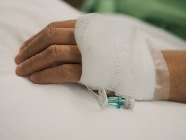 Hastalar yatakhanedeki koğuşta uyur. Hastanedeki kadının eline serum fizyolojik solüsyonu takın.