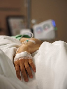 Hastalar yatakhanedeki koğuşta uyur. Hastanedeki kadının eline serum fizyolojik solüsyonu takın.