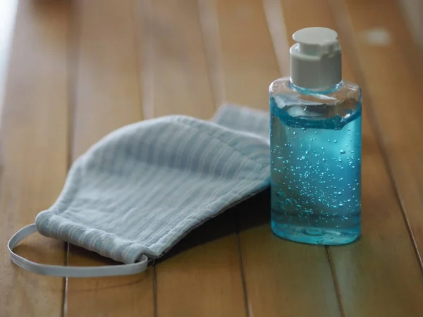 Plastik şişede el yıkama jeli, masa başı ahşap arka plan tozu üzerinde Mavi Maske kumaşı ve sonra mikroplar 2.5, virüs covid 19, Uv