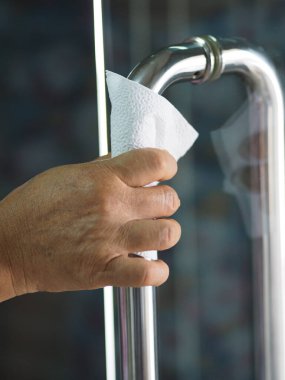 Paslanmaz çelikten kapıyı tutan dokuyu kullanan bir kadın Colona virüsünü korumak için kolona virüsünü koruyor.