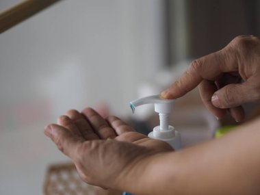 Ayakta duran ve pompa şişesine baskı yapan kadın, El Dezenfektanı, plastik şişede jelatinle karıştırılmış jel alkolü, Colona virüsünü korumak için kirli çamaşır, covid 19.