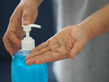 Ayakta duran ve pompa şişesine baskı yapan kadın, El Dezenfektanı, plastik şişede jelatinle karıştırılmış jel alkolü, Colona virüsünü korumak için kirli çamaşır, covid 19.