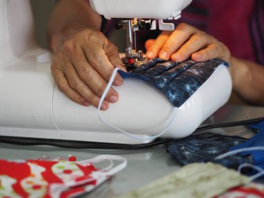 Evde oturan kadın, toz ve mikroplar için maske dikiyor. Öğleden sonra 2.5, virüs örtüsü 19.