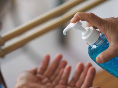 Kadının eli alkol jeli pompasının şişesine basıyor. Kolona virüsünü korumak için kiri temizlemek için başka bir ele verin.