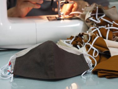 Evde oturan kadın, toz ve mikroplar için maske dikiyor. Öğleden sonra 2.5, virüs örtüsü 19.