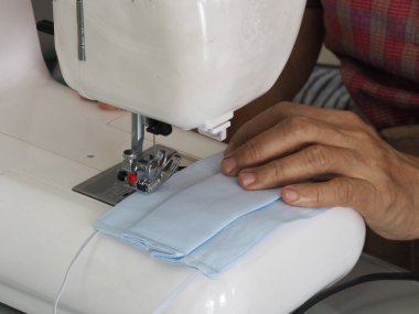 Evde oturan kadın, toz ve mikroplar için maske dikiyor. Öğleden sonra 2.5, virüs örtüsü 19.