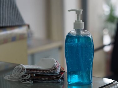 El dezenfektanı ve kumaş maskesi masada, jelatin ile saf plastik şişedeki jelatin karışımı temiz plastik şişeyle birlikte temiz çamaşır yıkama, mikropların bulaşıcı corona virüsünü koruması için kirli çamaşır yıkama, covid-19