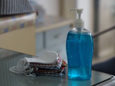 El dezenfektanı ve kumaş maskesi masada, jelatin ile saf plastik şişedeki jelatin karışımı temiz plastik şişeyle birlikte temiz çamaşır yıkama, mikropların bulaşıcı corona virüsünü koruması için kirli çamaşır yıkama, covid-19