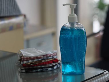 El dezenfektanı ve kumaş maskesi masada, jelatin ile saf plastik şişedeki jelatin karışımı temiz plastik şişeyle birlikte temiz çamaşır yıkama, mikropların bulaşıcı corona virüsünü koruması için kirli çamaşır yıkama, covid-19
