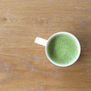 Portre bir fincan yeşil çay gün ışığına temiz ahşap tablo. metin tasarım için alan. Aroma aşk kafein koku.