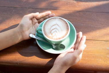 One coffee cup of hot black cappuccino on clean wooden table top