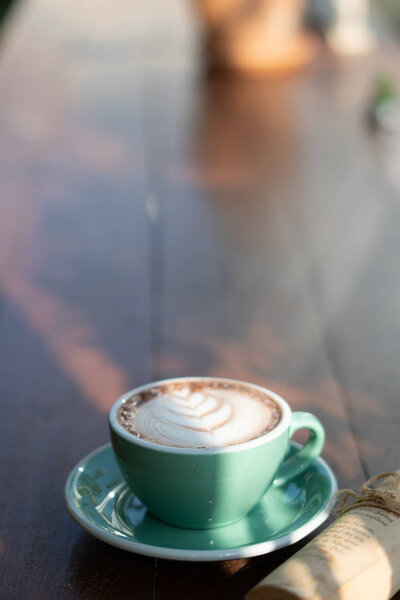 One coffee cup of hot black cappuccino on clean wooden table top