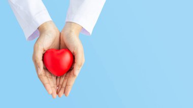 Kadın doktor elleri, hastanenin kan bakımı konsepti panoramik dünya kalp ve sağlık günü, CSR toplumu, çocuk organlarını desteklemek için geniş mavi arka planda kırmızı kalp bağışı yapıyor.