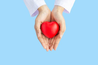 Kadın doktor elleri, hastanenin kan bakımı konsepti panoramik dünya kalp ve sağlık günü, CSR toplumu, çocuk organlarını desteklemek için geniş mavi arka planda kırmızı kalp bağışı yapıyor.