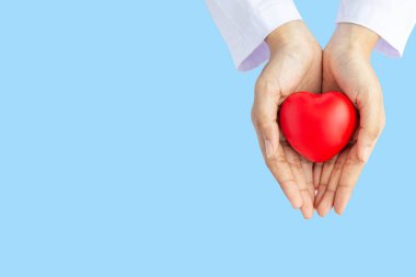 Kadın doktor elleri, hastanenin kan bakımı konsepti panoramik dünya kalp ve sağlık günü, CSR toplumu, çocuk organlarını desteklemek için geniş mavi arka planda kırmızı kalp bağışı yapıyor.