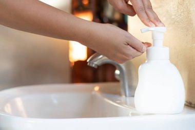 Asyalı anne kadınlar çocuklarını sabun alkolü jeliyle yıkıyor mutfak lavabosu konseptiyle hijyen sağlığını engelliyor. Karantina altındaki çocuklar mikrop ve mikrop salgını Coronavirus 19 'a yayıldı.
