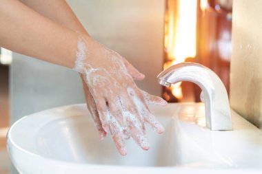 Asyalı anne kadınlar çocuklarını sabun alkolü jeliyle yıkıyor mutfak lavabosu konseptiyle hijyen sağlığını engelliyor. Karantina altındaki çocuklar mikrop ve mikrop salgını Coronavirus 19 'a yayıldı.