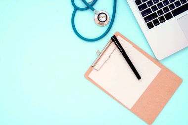 Hastane işyeri için düz mavi masa üstü görünümü arka plan konsepti üzerinde antika stetoskop doktor ekipmanı modeli, klinik nesne aletini izole et, modern masaüstü boş dizüstü bilgisayar alanı.