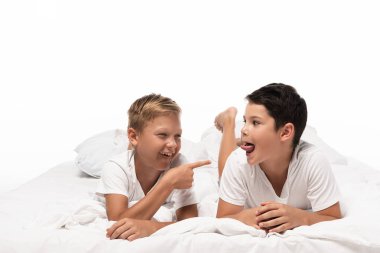 cheerful boy pointing with finger at brother sticking out tongue isolated on white clipart
