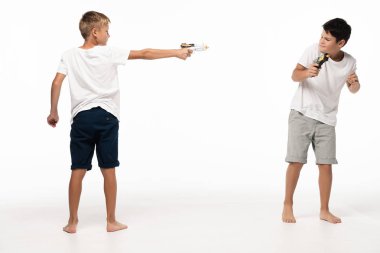  boy aiming with toy gun at scared brother on white background clipart