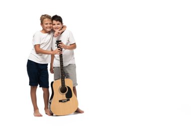 İki kardeş kameraya bakıyor ve beyaz arka planda kulaklıkla müzik dinlerken dans ediyorlar.