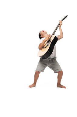 Gitar çalan ve beyaz arka planda şarkı söyleyen heyecanlı çocuk.