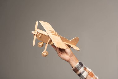 Gri üzerinde izole edilmiş ahşap oyuncak uçak tutan çocuk görüntüsü.