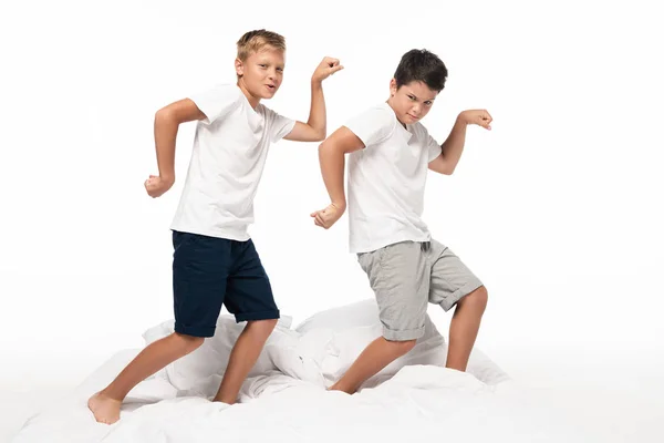 Dois Irmãos Alegres Imitando Fisiculturistas Enquanto Cama Isolado Branco — Fotografia de Stock