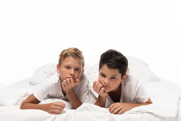 Dos Hermanos Pensativos Acostados Cama Sonriendo Cámara Aislados Blanco — Foto de Stock