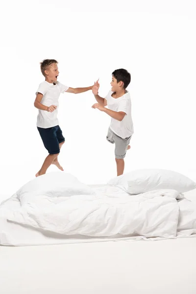 Two Excited Brothers Levitating Bed Looking Each Other Isolated White — Stock Photo, Image