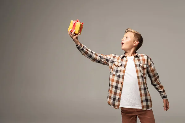 Niño Sorprendido Sosteniendo Caja Regalo Mano Extendida Aislada Gris — Foto de Stock