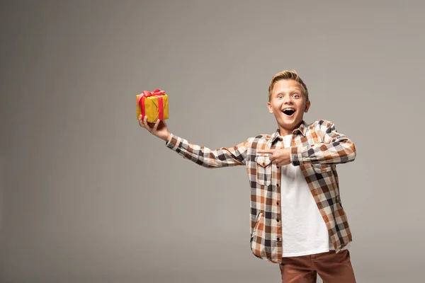 Amazed Boy Pointing Finger Gift Box Looking Camera Isolated Grey — Stock Photo, Image