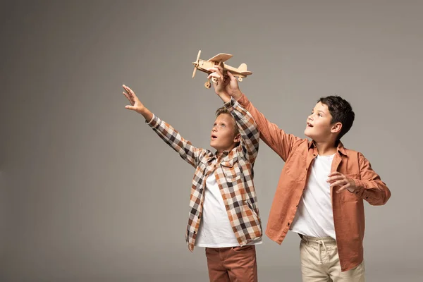 Two Happy Brothers Holding Wooden Toy Plane Raised Hands Isolated — Stock Photo, Image