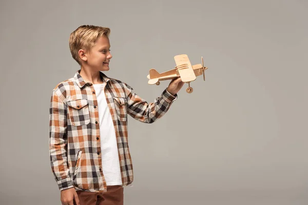 Menino Sorrindo Segurando Avião Brinquedo Madeira Isolado Cinza — Fotografia de Stock