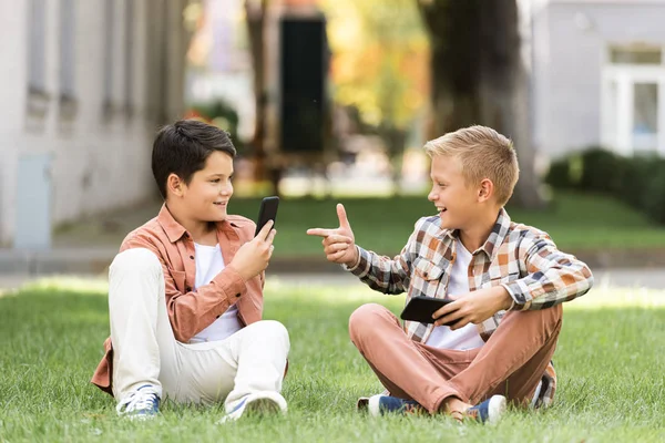 Alegre Chico Apuntando Con Dedo Sonriente Hermano Mientras Sentado Juntos —  Fotos de Stock