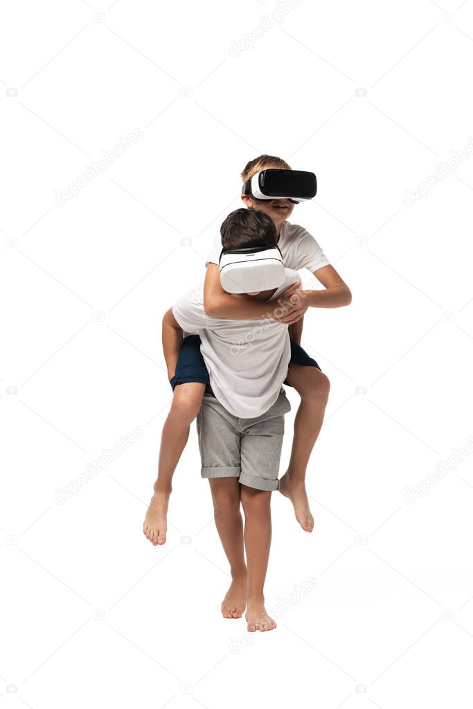 boy piggybacking brother while using vr headsets together on white background