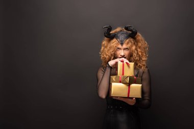 Kötü niyetli kostümlü korkunç kadın, cadılar bayramı için hediye kutuları tutuyor.