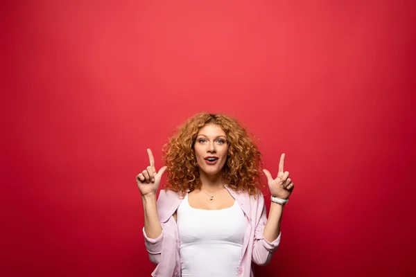 Bela Mulher Ruiva Animado Apontando Para Cima Isolado Vermelho — Fotografia de Stock