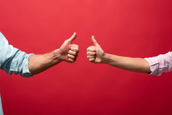 partial view of couple showing thumbs up, isolated on red