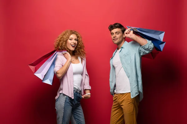 Cheerful Couple Holding Shopping Bags Isolated Red — Stock Photo, Image