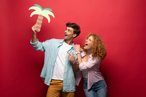 Casal Viajantes Felizes Segurando Palma Papel Isolado Vermelho — Fotografia de Stock