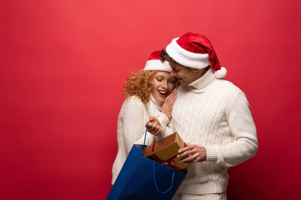 Casal Feliz Chapéus Santa Com Presente Saco Compras Isolado Vermelho — Fotografia de Stock