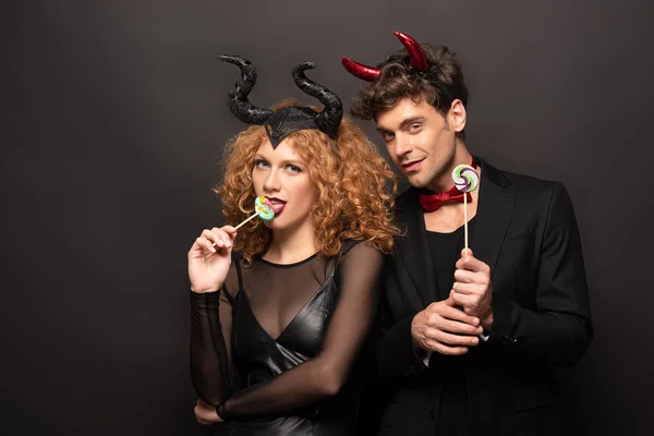 セクシーカップルでハロウィン衣装食べるロリポップオン黒 — ストック写真