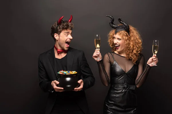这对年轻貌美的夫妇穿着夹杂着香槟酒和黑色糖果的服装摆设在一起 — 图库照片