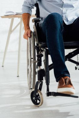 Tekerlekli sandalyede el ele tutuşan adamın görüntüsü.